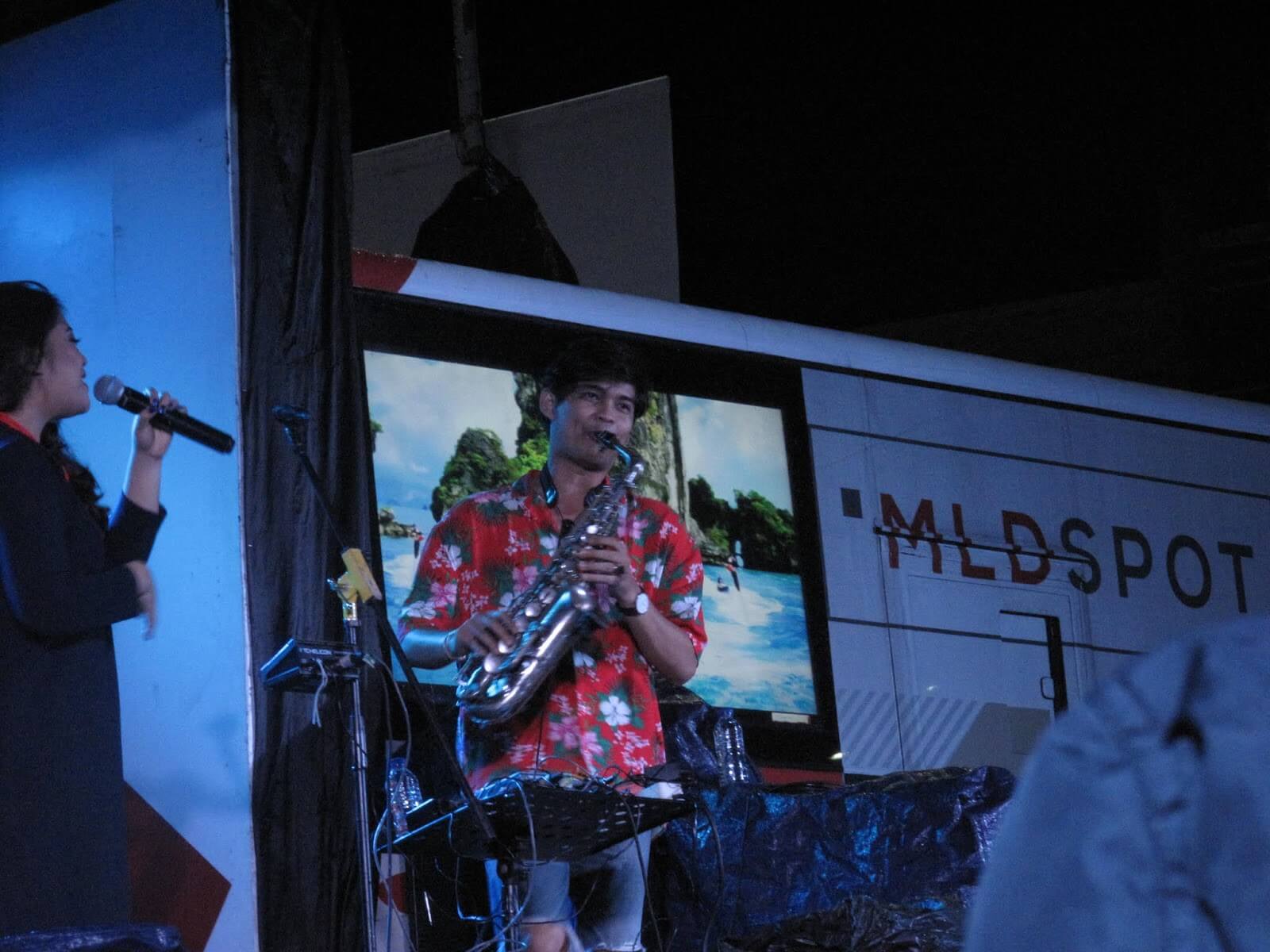 Erick Giri mengenakan kemeja bunga-bunga sedang meniup saxophone